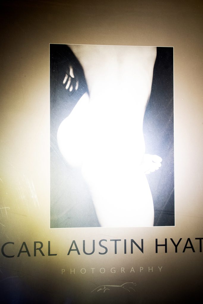 High-contrast black-and-white photograph of a nude torso flooded with bright light against dark shadow.