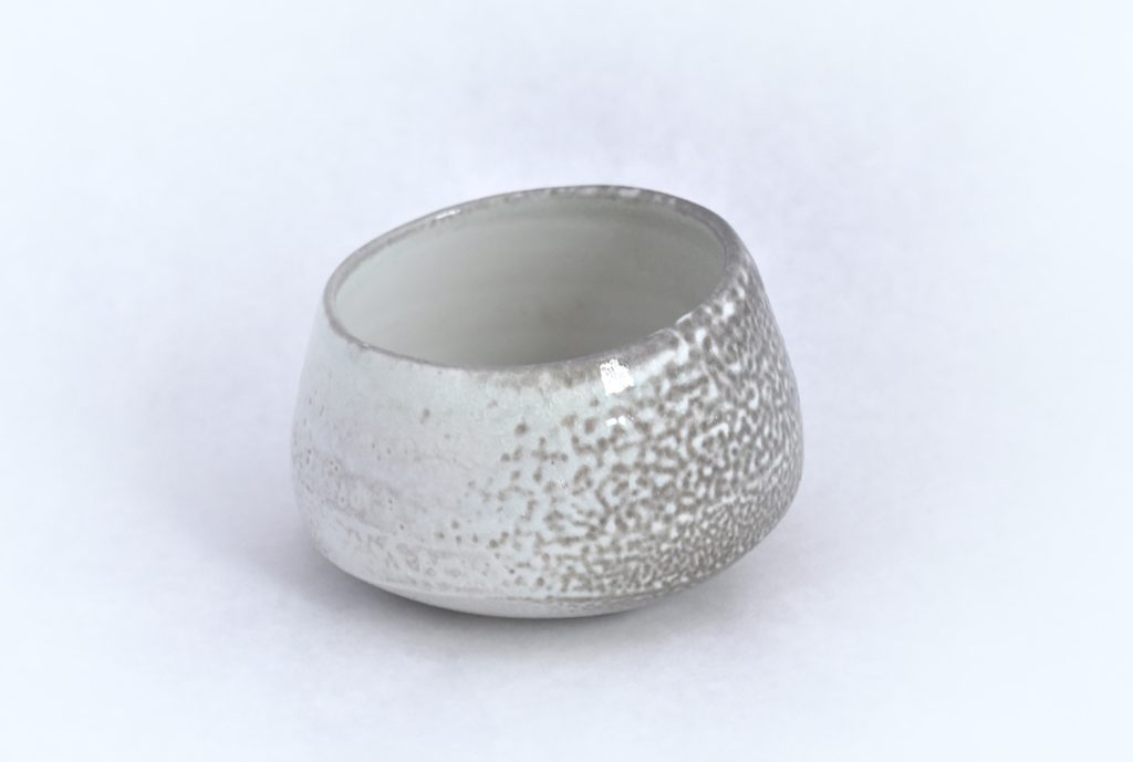 Small squat ceramic bowl with a speckled white and grey soda-fired glaze on a white background.