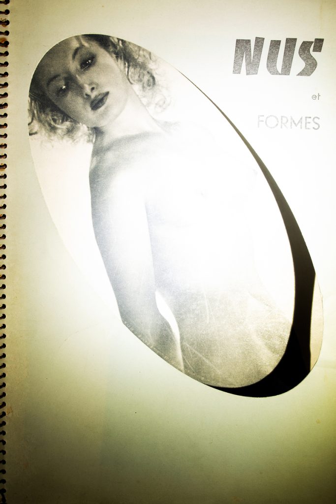 Archival pigment print of a female nude figure in an oval vignette beside bold French typographic text on cream paper.