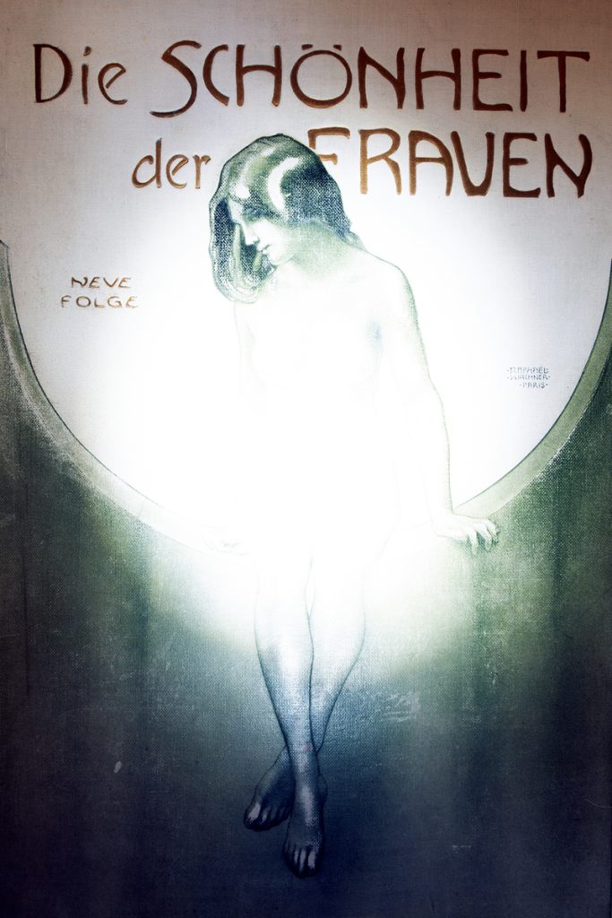 Archival print of a nude female figure seated within a glowing oval of white light, framed by green drapery and German text.