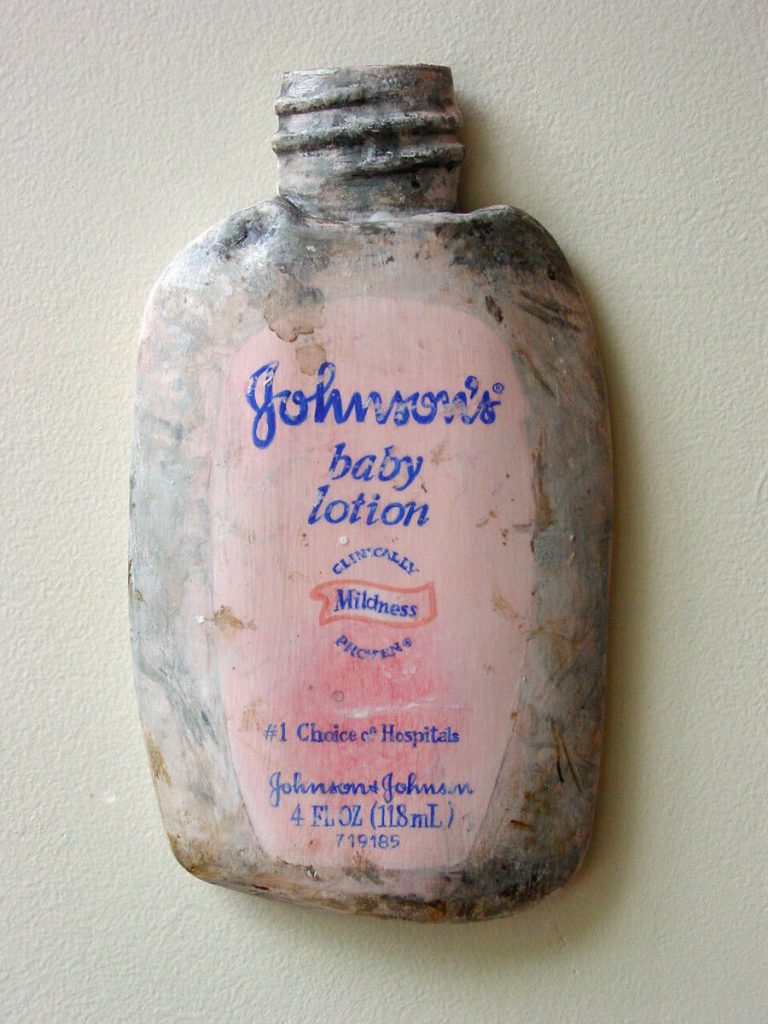Three-dimensional acrylic painting on shaped wood of a worn Johnson's Baby Lotion bottle mounted on a wall.