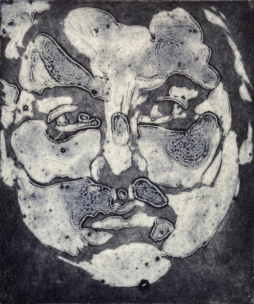 Collagraph print of a fragmented, biomorphic face-like form in dark grey and white on a charcoal ground.